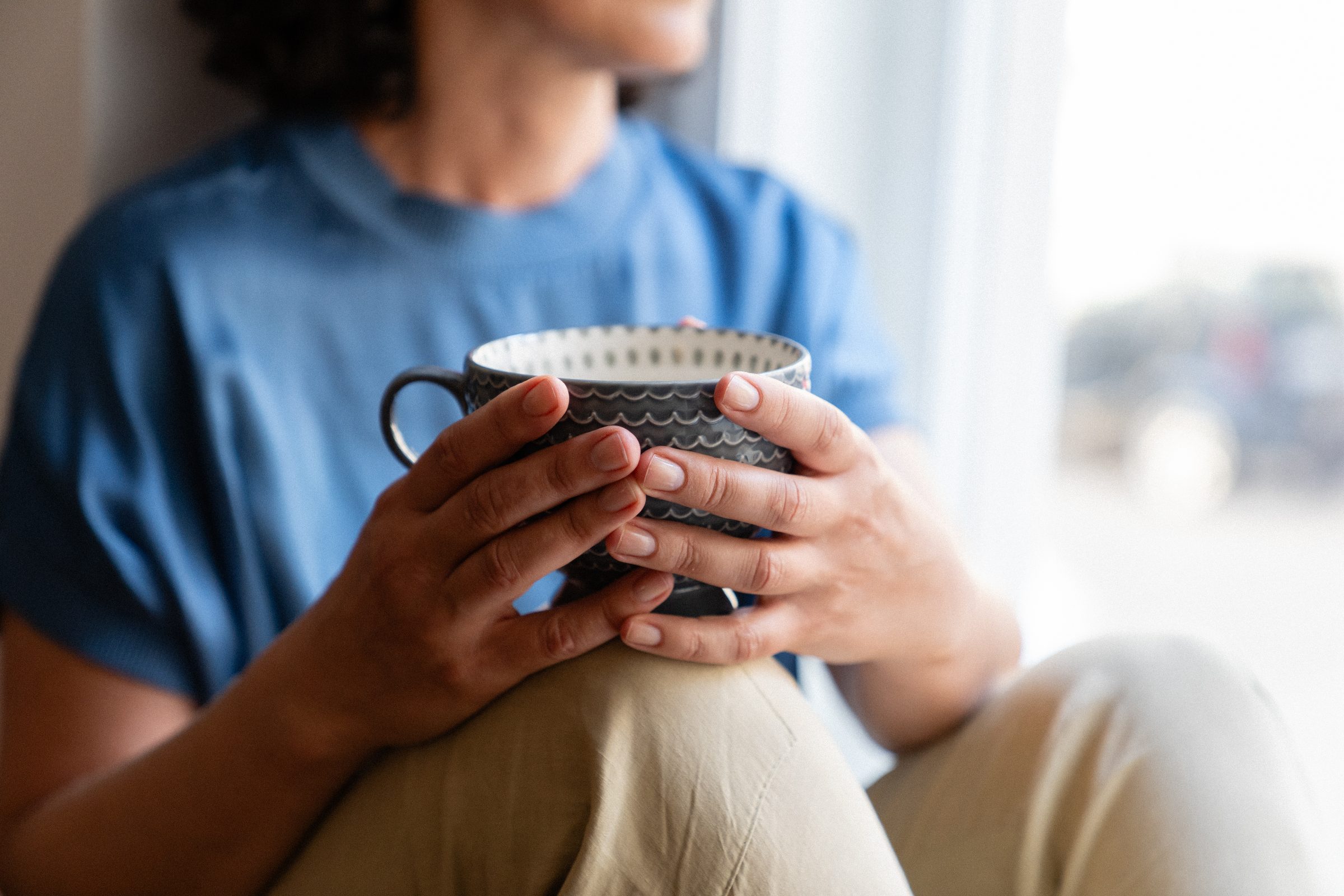 Frau am Fenster mit Teetasse